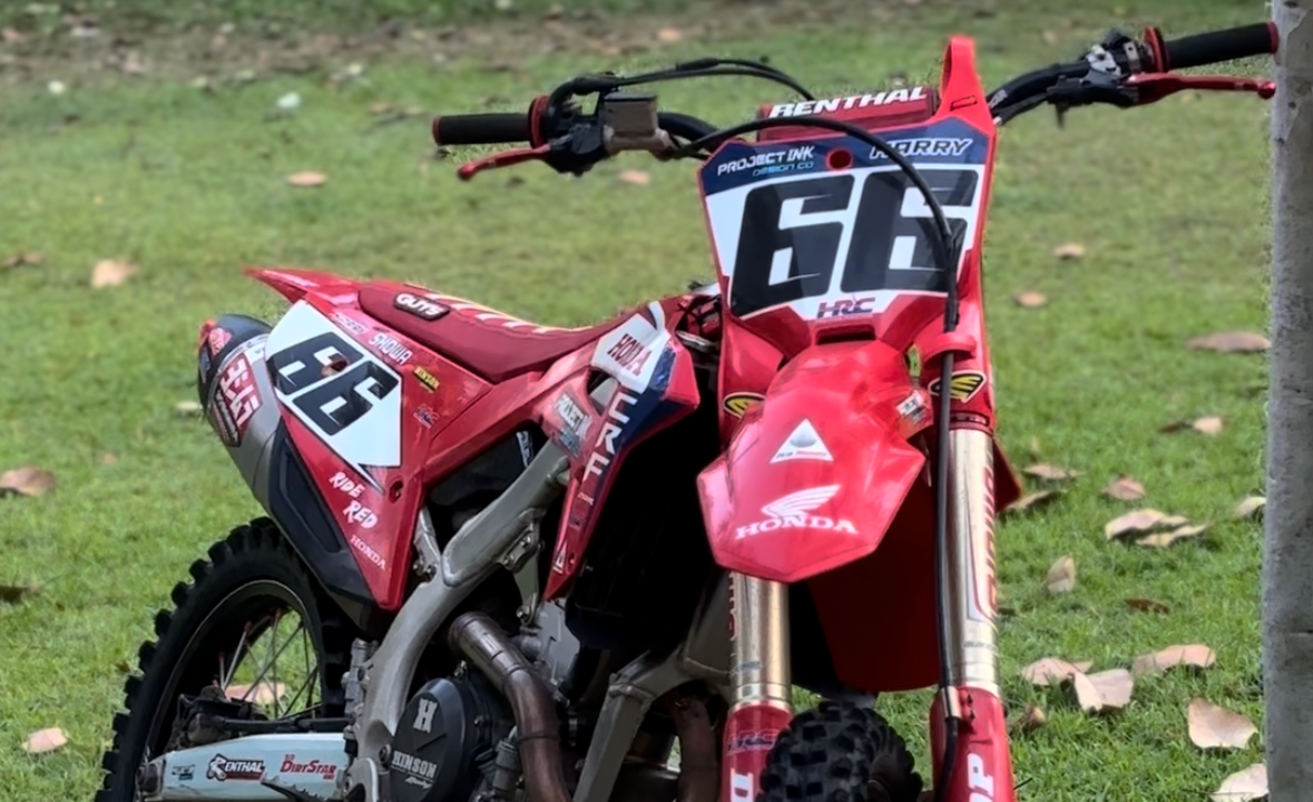 Red dirt bike with number 66 on a grassy area